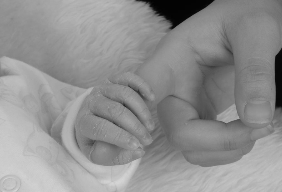 Tiny baby holding hand in Captured Moment Portrait Studio